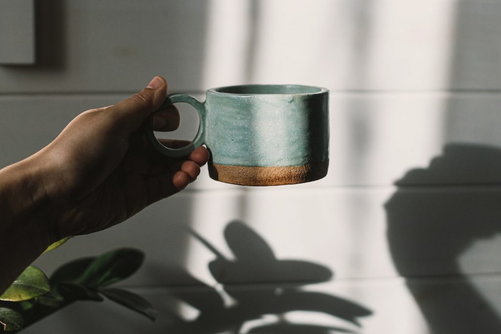 Hand holding stylish cup in sunlight. Morning coffee aesthetics
