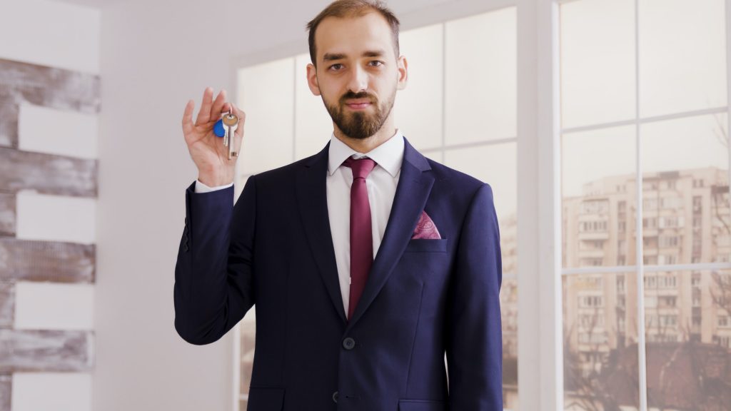 Real estate agent in business suit smiling and showing apartment key
